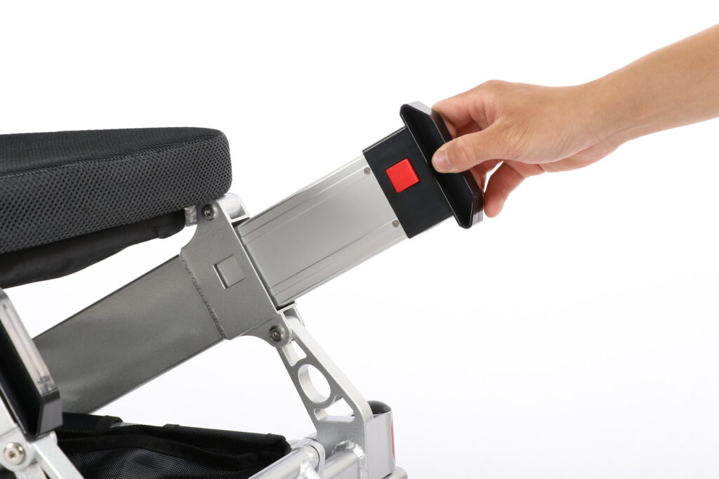 Ranger Maestro reclining folding power wheelchair, hand holding a pack with red button at the frame tube end under the seat