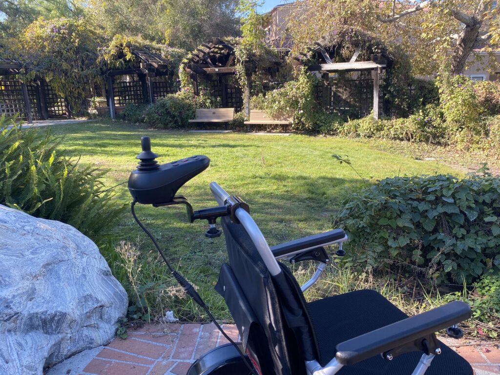 Ranger Discovery Caregiver power wheelchair, caregiver joystick on the push handle seen from behind the chair